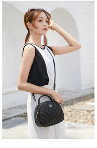 Detail of black quilted crossbody bag with golden flower buckle on a fashion model