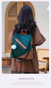 Detail view of dark green waterproof backpack with anti-theft zipper and pompom charm