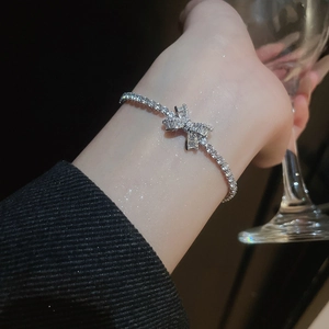 Macro shot of silver bow bracelet with sparkling cubic zirconia on a female wrist