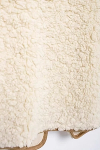 Close-up of cream curly fleece texture with premium brown faux leather piping detail