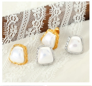 Detailed macro view of gold and silver irregular square pearl stud earrings on lace