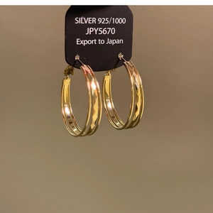 Macro shot of gold-plated 925 silver triple hoop earrings with diamond-cut texture details
