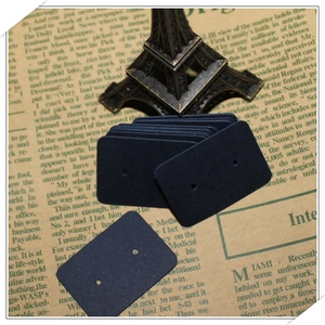 Close-up of black cardboard earring display cards on vintage newspaper background