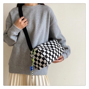 Chic black and white checkerboard barrel bag with wide shoulder strap on model