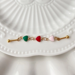 Macro view of gold chain industrial piercing with colorful heart pendants on ceramic