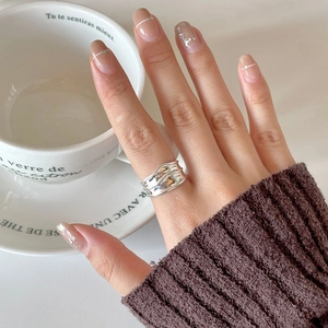 Close-up of minimalist silver wave ring worn on finger with elegant French knit sleeve