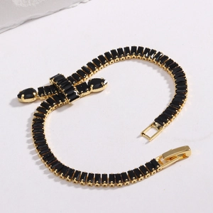 Tennis chain bracelet with black zircons and gold cross pendant on white background