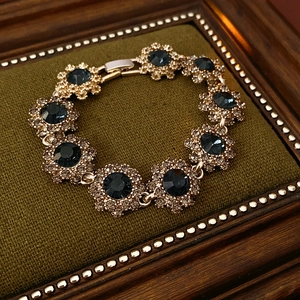 Gros plan du bracelet fleur vintage avec pierres vertes et diamants sur velours