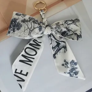 Detail view of camellia silk scarf keychain with cream floral ribbon and gold ring