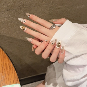 Handmade almond press-on nails with champagne rhinestones and metal bow charms