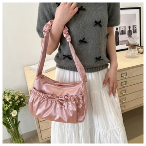 Detail of pink satin shoulder bag featuring sweet bow drawstring and ruched strap