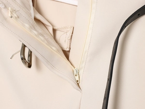 Macro detail of the metal zipper and hook closure on beige casual trousers