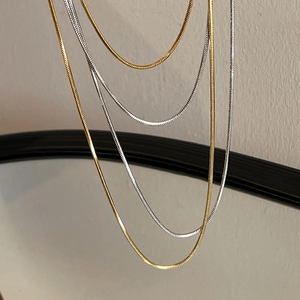 Detailed view of layered gold and silver snake bone chain necklaces with metallic finish