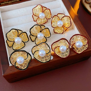 Close-up of gold-plated flower earrings with white pearls in a wooden jewelry box