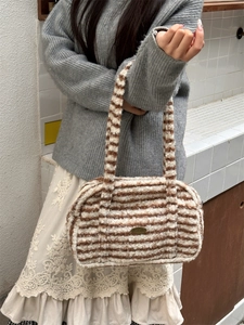 Detail view of plush striped Boston bag with brown and white faux fur and metal logo
