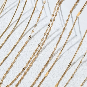 Golden stainless steel necklace set with various chain styles on white texture background