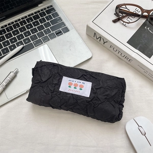 Detail of black pleated fabric pencil case with tulip embroidery and zip closure
