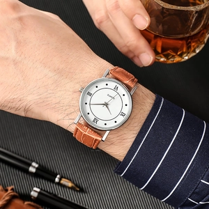Detail of classic silver men's watch with brown leather strap in a professional business setting