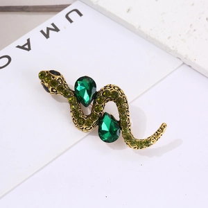 Detail of vintage snake brooch with green pavé crystals and emerald pear stones