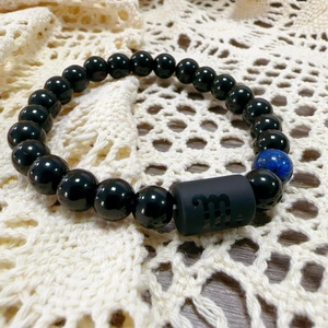 Macro shot of Virgo zodiac bead with black obsidian and blue natural stone beads