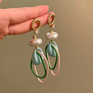 Detail view of colorful resin hoop earrings with water drop pearls and gold hooks