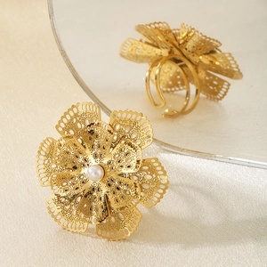 Détail d'une bague fleur dorée avec pétales évidés et perle centrale incrustée