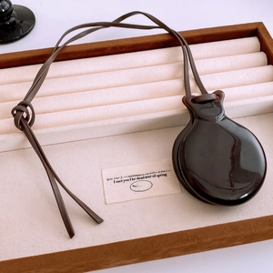 Detail of vintage mirror pendant on dark brown leather cord in a velvet tray