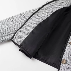 Detail of tweed jacket featuring golden metal buttons and high-quality black inner lining