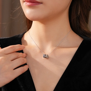 Close-up of a silver double-ring zircon pendant necklace worn on a woman's neck