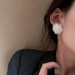 Detail view of cluster pearl stud earrings in flower shape on a female model