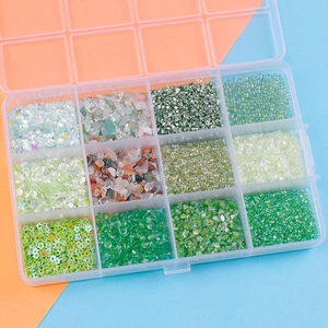 Top-down macro view of 12-grid box with green craft sequins and glass stone beads