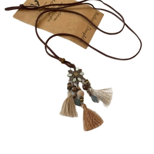 Zen style bohemian tassel necklace with flower metal charms and wooden beads on white base