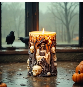 Macro detail of Halloween witch and skull relief on cylinder candle with a lit flame