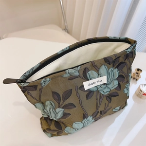 Detail of floral makeup bag featuring vintage olive jacquard pattern and a zipper closure