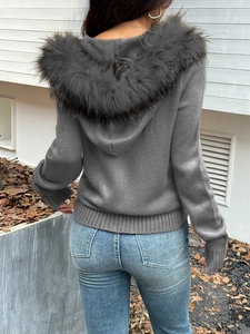 Rear view of dark grey knitted hooded cardigan with faux fur trim collar in an outdoor setting