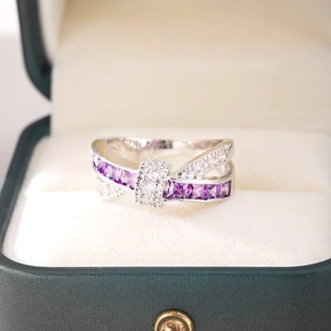 Macro shot of silver crossover ring featuring purple square gemstones and white zircon accents
