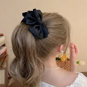 Elegant large black satin bow hair clip for women, perfect for high ponytail styling