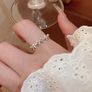 Detail of silver bow-shaped interlocking rings worn with elegant lace and glass decor