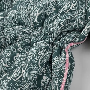 Detail of dark green paisley jacket fabric with pink piping and intricate white patterns