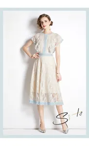 Detailed close-up of lace embroidery with light blue scalloped trim on beige dress