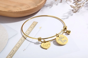 Detailed view of adjustable gold heart bracelet with Love mi mama charms on wooden tray