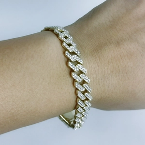 Hip hop gold Cuban link bracelet with sparkling diamonds on a wrist against white background