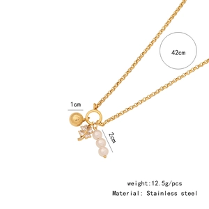 Dettaglio della collana a cuore in acciaio inox con perle dorate, quadrifoglio e perle