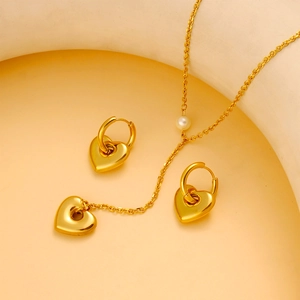 Golden heart jewelry set featuring necklace with pearl and matching earrings on elegant backdrop
