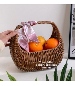 Detail of woven rattan tote bag with floral silk scarf handle holding fresh oranges
