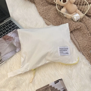 Close-up of minimalist white waterproof storage bag with a bright yellow zipper accent