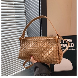 Dettaglio della trama in pelle intrecciata di una borsa a tracolla color cammello