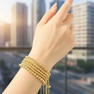 Detailed view of layered 18K gold-plated beaded bracelets with adjustable slider on wrist