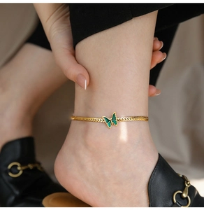 Close-up of 18K gold plated snake chain anklet with green enamel butterfly charm