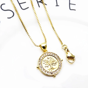 Close-up of a gold-plated Tree of Life pendant with pavé zircon stones on a box chain